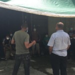 Workers unloading container about to pray before starting work. Cuban officials present for inspection as items are unloaded.